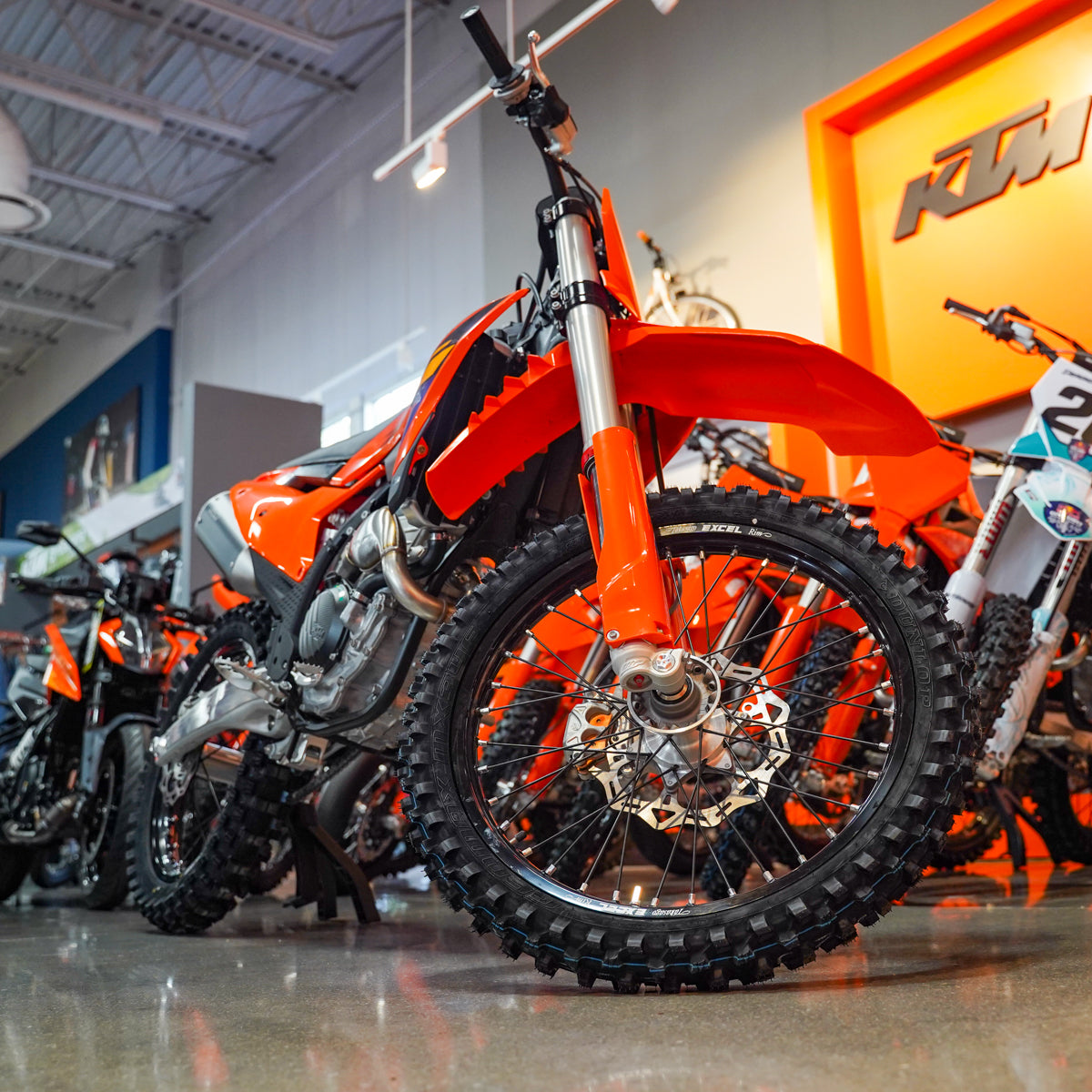 Row of orange dirt bikes in a showroom with KTM logo.