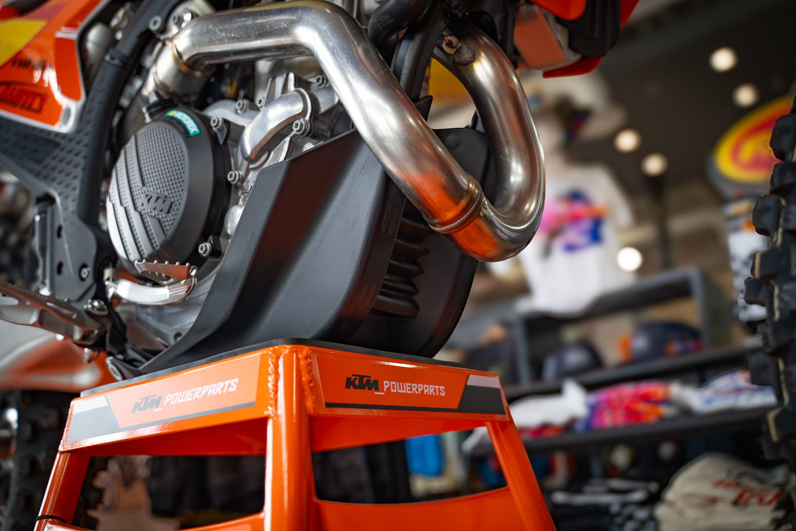 Close-up of a motorcycle engine with 'KTM Powerparts' branding in a store setting and skid plate