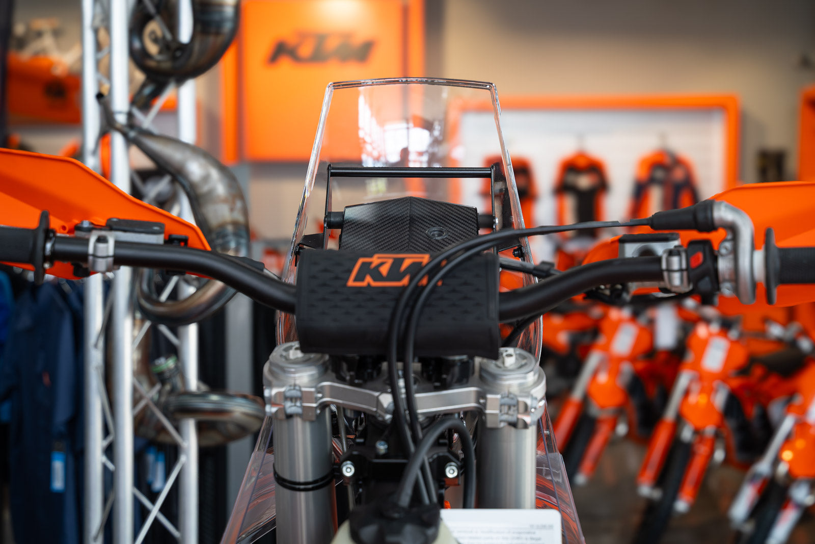 Close-up of a KTM motorcycle with a clear windshield in a showroom setting.