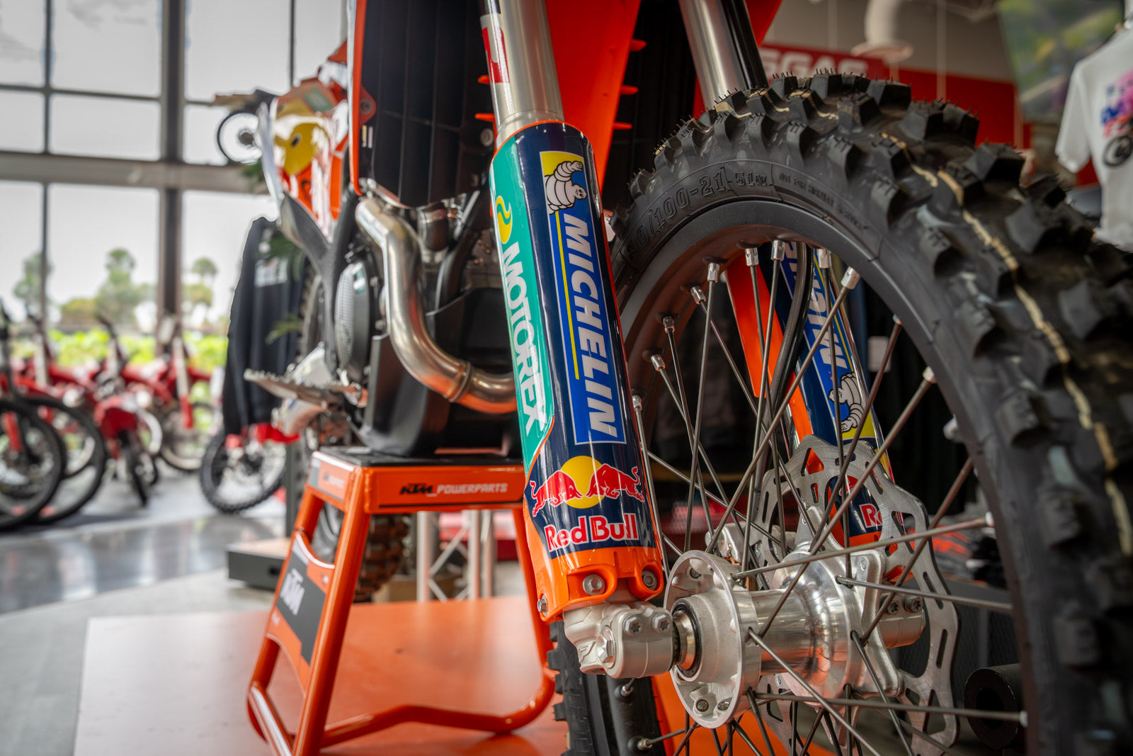 Close-up of a dirt bike with Michelin and Red Bull branding in a showroom setting.