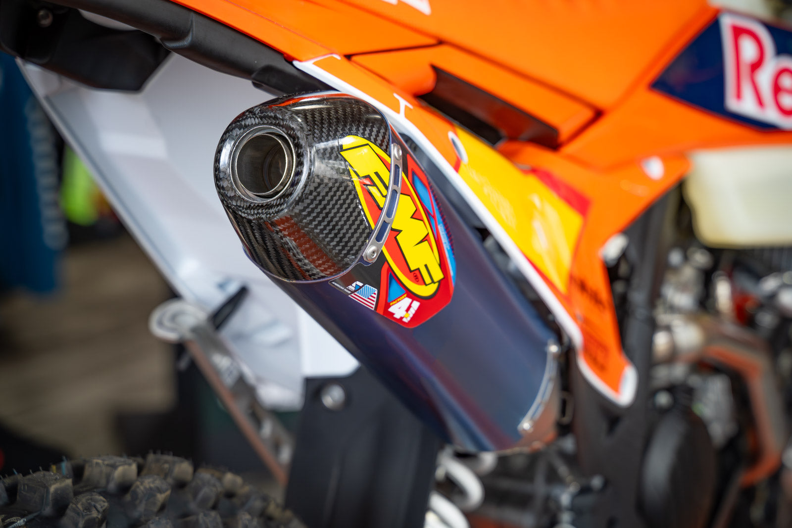 Close-up of a motorcycle FMF 4.1 exhaust with a brand logo on an orange background