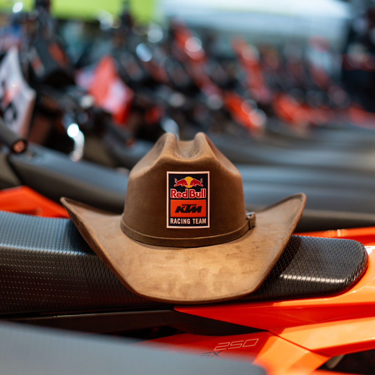Brown cowboy hat with Red Bull KTM Racing Team logo on a motorcycle seat.