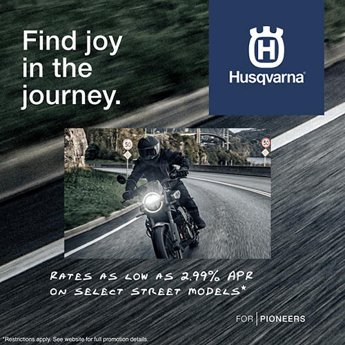 Husqvarna motorcycle advertisement with a rider on a road, featuring the brand logo and promotional text.