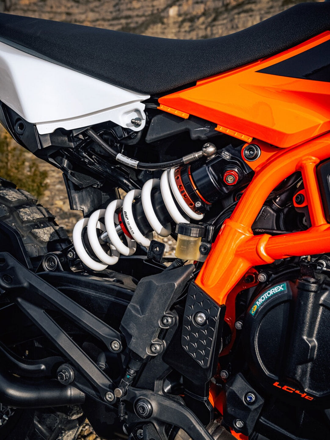 Close-up of a motorcycle with orange and black frame, white suspension, and visible brand logo. WP Suspension Shock for KTM 390.